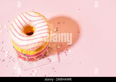 Parchment with different delicious donuts on pink background Stock Photo