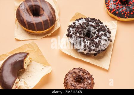 Parchments with different delicious donuts on beige background Stock Photo