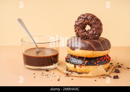 Parchment with delicious chocolate donuts and glass of pudding on beige background Stock Photo