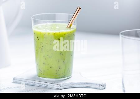 Green smoothie in glass served with straw. Made from kiwi and chia seeds. Super food and antioxidant for healthy lifestyle Stock Photo