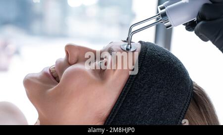 Young caucasian woman on microcurrent therapy procedure. Beautician's office. Stock Photo