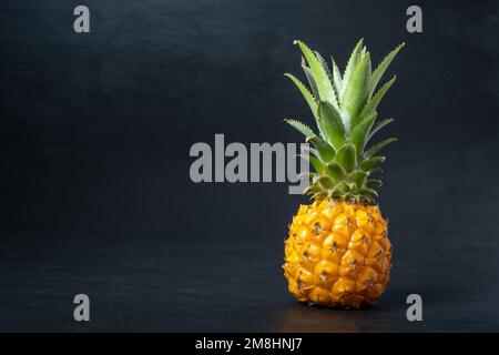 Ripe mini baby pineapple over dark background. Stock Photo