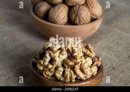 Peel walnuts and whole walnuts on burlap sack Stock Photo