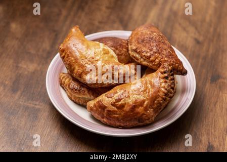 Plate with puff pastry sweets stuffed with angel hair on a wooden table. Stock Photo