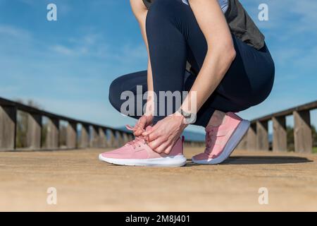female tying up laces on running shoes, preperation before jogging. Stock Photo