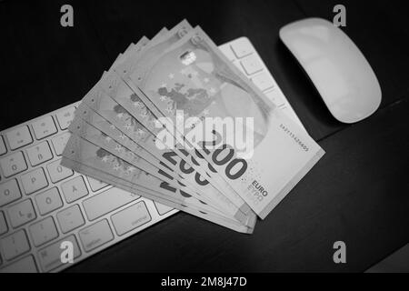 some 200 euro banknotes are lying next to a computer keyboard Stock Photo