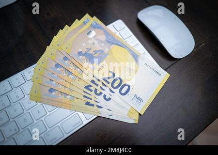some 200 euro banknotes are lying next to a computer keyboard Stock Photo