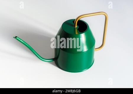 Small decorative green watering can with a yellow handle for watering houseplants on a white background. Stock Photo