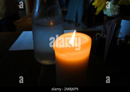 Close-up of a burning candle in a restaurant setting - John Gollop Stock Photo