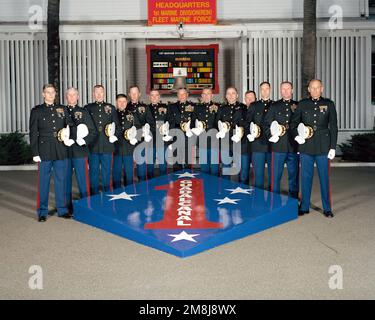 Exterior, MLS, MG Charles E. Wilhelm, USMC, Commanding General 1ST Marine Division and 12 Regimental Commanders, in dress blues and holding hats, line up on two sides of a large replica of the 1ST Marine Division Patch and Seal. In background behind the staff is a sign, 'HEADQUARTERS 1ST MARINE DIVISION (REIN) FLEET MARINE FORCE'. Behind the staff is a large plaque showing the 1ST marine Division's Decorations and a ship's bell. The bell is from the USS WHARTON (AP-7) a WW II Troop Transport. The ship was named for the third Commandant of the Marine Corps, LTC Frank Wharton. Base: Marine Corps Stock Photo