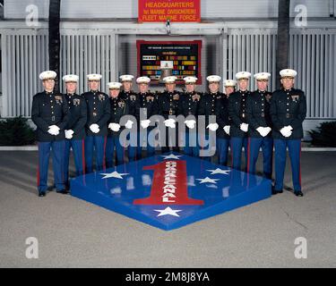 Exterior, MLS, MG Charles E. Wilhelm, USMC, Commanding General 1ST Marine Division and 12 Regimental Commanders, in dress blues, line up on two sides of a large replica of the 1ST Marine Division Patch and Seal. In background behind the staff is a sign, 'HEADQUARTERS 1ST MARINE DIVISION (REIN) FLEET MARINE FORCE'. Behind the staff is a large plaque showing the 1ST marine Division's Decorations and a ship's bell. The bell is from the USS WHARTON (AP-7) a WW II Troop Transport. The ship was named for the third Commandant of the Marine Corps, LTC Frank Wharton. Base: Marine Corps Base Camp Pendle Stock Photo
