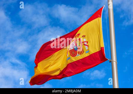 Spanish flag blowing in the wind against a blue sky with clouds and copy space. Spain Square (Plaza de Espana), Madrid downtown, Spain, Europe. Stock Photo