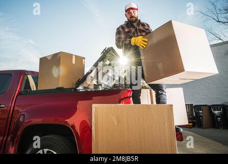 Caucasian Man Moving Boxes To His New Apartment. Transporting Carton Boxes on a Pickup Truck. Stock Photo