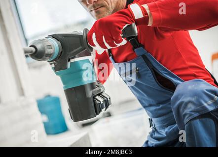 Concrete Hole Drilling by Construction Worker Using Professional Heavy Duty Drilling Equipment. Concrete Bricks Built House. Stock Photo