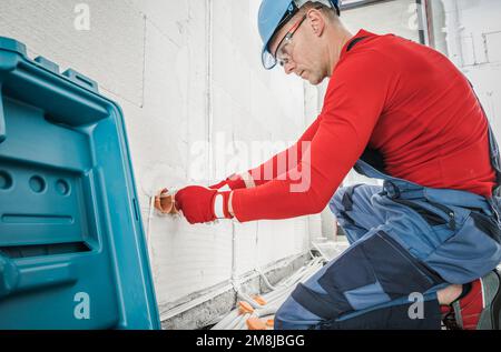 Professional Electrician Contractor Installing Electric Socket Inside Newly Built House. Stock Photo