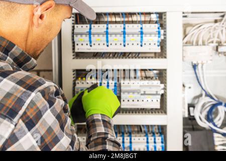 Caucasian Electrician Contractor Installing Residential Electric Fuse Box. Power Supply Technologies Theme. Stock Photo