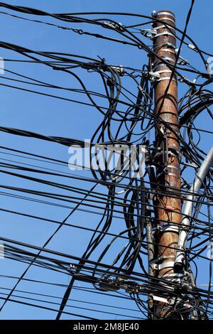 chaotic and crowded power lines on a blue sky background Stock Photo