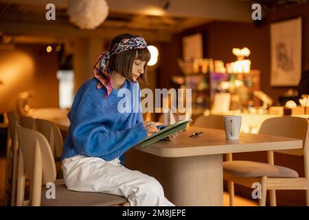 Woman works on touchpad at coffee shop Stock Photo