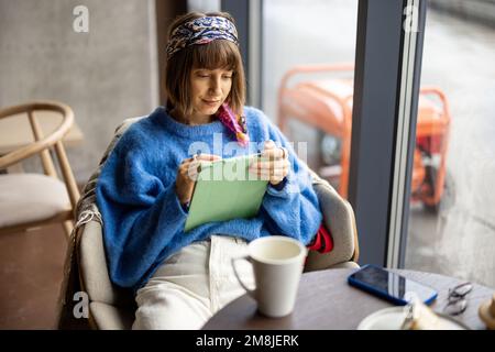 Woman works on tablet in cafe with a generator outdoors Stock Photo