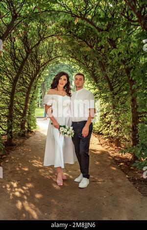 Portrait of the happy bride and groom under the green flowering arch close-up. A joyful couple in the spring garden Stock Photo