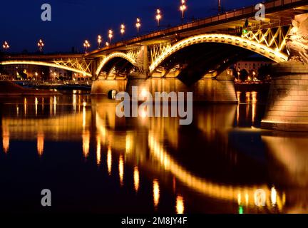 the Margaret bridge in Budapest at dusk. perspective side view. brightly illuminated steel arches. reflection on the water. tourism and travel concept Stock Photo