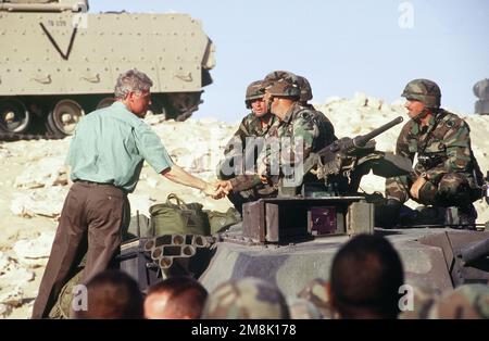 President William Jefferson Clinton stands on an M-1A1 Abrams tank to shake hands with the tank crew from C Company, 369th Armor, Fort Stewart, Georgia, after his speech to American and Kuwaiti troops deployed at Tactical Assembly Area Liberty. Subject Operation/Series: VIGILANT WARRIOR Base: Kuwait City Country: Kuwait (KWT) Stock Photo