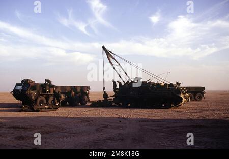 US soldiers use a tank recovery vehicle to load mine plows for the M1A1 Abrams Tank onto an M977 heavy expanded mobility tactical truck (HEMTT) in the desert of Kuwait. Subject Operation/Series: VIGILANT WARRIOR Country: Kuwait (KWT) Stock Photo