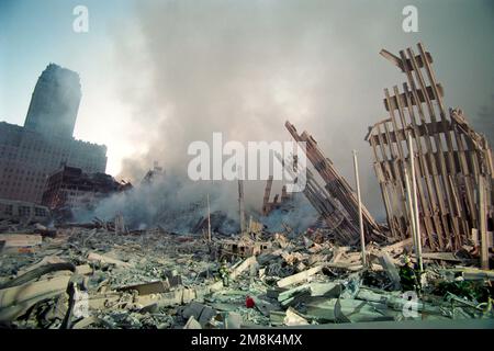 New York City firefighters are dwarfed as they are surrounded by devastation as the sun rises on the morning of September 12th, 2001 following the att Stock Photo