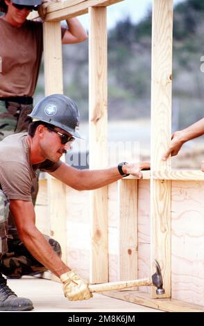 US Navy Seabees from Naval Mobile Construction Battalion 4 (NMCB-4) and Cuban migrant carpenters construct hard backed tent frames for village Bravo at Camp Bulkeley. The construction is one solution in an effort to improve the quality of life for the migrants. Subject Operation/Series: SEA SIGNAL Base: Guantanamo Bay Country: Cuba (CUB) Stock Photo