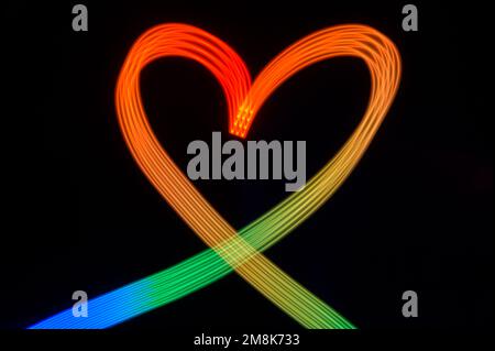 Rainbow colored light painted heart on black background Stock Photo