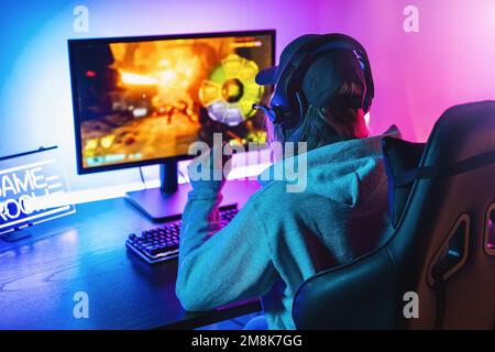 Man playing multiplayer online action game while gaming girl is fighting in  virtual reality game at home. Gamer streaming first person shooter on pc  while girlfriend uses vr goggles for simulation Stock