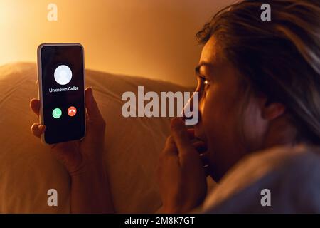 Unknown number calling in the middle of the night. Phone call from stranger. Woman holding smartphone in bad late. Unexpected call disturbs at night Stock Photo