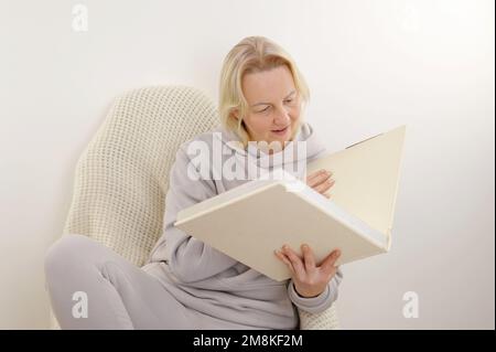 Woman is flipping through an album with blank pages. Woman's hand slowly turns the page of a clean book notebook with beige pages. Looking through a f Stock Photo