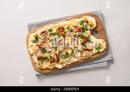 Trendy Butterboard with olives, sun-dried tomatoes, nuts, onion and herbs with crispy bread on white background. View from above. Stock Photo