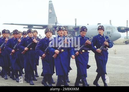 At Otopeni Air Base, Bucharest, Romania, Romanian airmen march off after the conscript swearing-in ceremony. In the background is the C-130 from the 37th Airlift Squadron, Ramstein Air Base, Germany that transported an Air Force airfield survey team. The base was visited by the airfield survey team at the request of Romanian officials to determine if Romanian bases meet US and NATO standards for use in operations and exercises. Base: Otopeni Air Base, Bucharest Country: Romania (ROM) Stock Photo