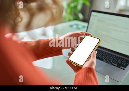 Woman holding using mobile phone with mock up screen, over shoulder view. Stock Photo