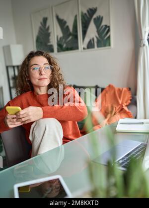 Young woman using phone studying or remote working at home. Vertical Stock Photo
