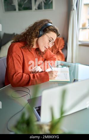 Young woman university student wearing headphones using laptop elearning. Stock Photo