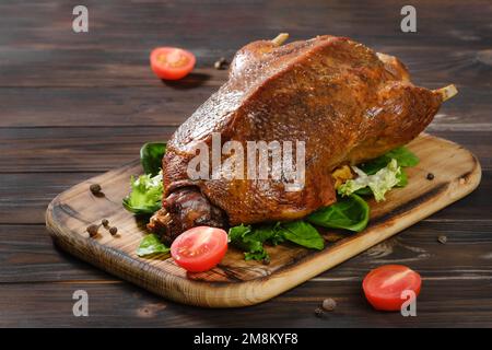 Whole roast duck and vegetables on a dark wooden board. horizontal view from above Stock Photo
