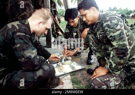 Soldiers from the 5th Long Range Reconnaissance Patrol Company, Royal Thai Army, share field chow with a soldier from the US Army's 6th Infantry Division during the cross training phase of Exercise COBRA GOLD '96. Subject Operation/Series: COBRA GOLD '96 Base: Nakhon Si Thammarat Country: Thailand (THA) Stock Photo