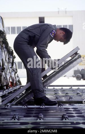 STAFF SGT. Roland Reves, loadmaster, 21st Airlift Squadron, Travis Air Force Base, CA, flips over roller plates on a C-5 Galaxy to facilitate the offloading of four Army helicopters, two cargo pallets and a government vehicle for use during Roving Sands '96, the US military's largest annual joint air defense training exercise. Subject Operation/Series: ROVING SANDS '96 Base: Biggs Army Air Field, El Paso State: Texas (TX) Country: United States Of America (USA) Stock Photo