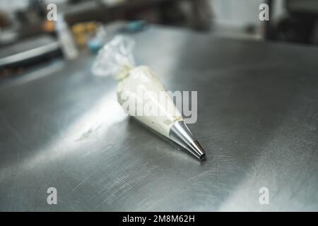 view of white glazing for gingerbread, brownies and cakes in a pastry bag on a kitchen table, cake decorating tool. High quality photo Stock Photo