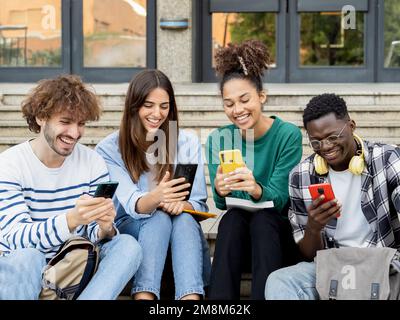 Group of smiling diverse students browse social networks with smart phones. Social media concept Stock Photo
