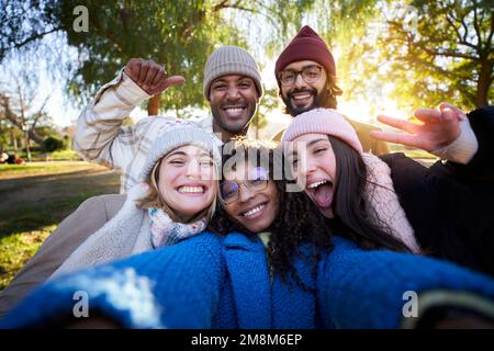 Winter time smiling selfie of a happy group of multicultural friends looking at the camera. Stock Photo
