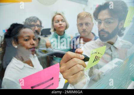 Creative colleagues meeting in office. Business people team brainstorming, writing on paper note.  Stock Photo