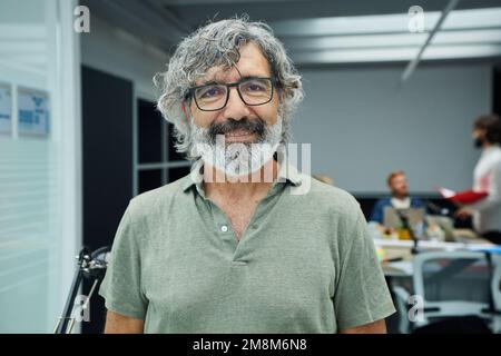 Smiling mature businessman looking camera standing in office at team board meeting Stock Photo