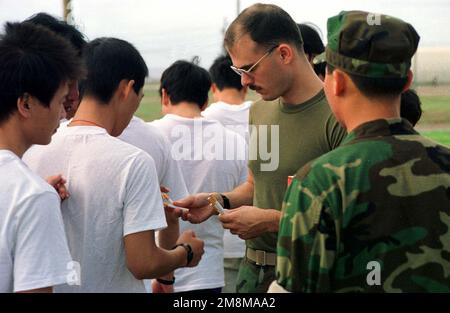 A US Army joint task group (JTG) member hands out cigarettes to each Chinese migrant who smoke. This United States Atlantic Command operation deployed the Air Contingency Force of II Marine Expeditionary Force (MEF), to process over 100 Chinese migrants. Subject Operation/Series: OPERATION MARATHON Base: Guantanamo Bay Country: Cuba (CUB) Stock Photo