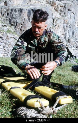 Dive MASTER Medical Surgeon Commander Leland J. Morrison inspects equipment that he may need in case of a medical emergency when members of the Naval Explosive Ordnance Disposal Mobile Unit 7 from San Diego, California search the lakes for the missing bombs carried by the A-10 that crashed on nearby Gold Dust Peak. Base: Big Spruce Lake State: Colorado (CO) Country: United States Of America (USA) Stock Photo