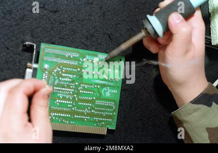 With a soldering iron, the skilled hands of a maintenance technician, with the 55th Communications Squadron, repairs a circuit board in the Offutt Air Force Base Visual Information Maintenance section. (Substandard image). Base: Offutt Air Force Base State: Nebraska (NE) Country: United States Of America (USA) Stock Photo