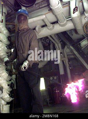 US Navy Machinist's Mate Third Class Dwan Barsh prepares to light an engine boiler aboard Forrestal Class Aircraft Carrier, USS INDEPENDENCE (CV 62) while the ship is on deployment to the Persian Gulf as part of Southwest Asia build-up. Base: USS Independence (CV 62) Stock Photo